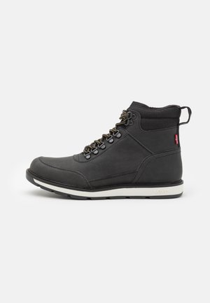 Schwarze wasserdichte Stiefel mit einem glatten Lederoberteil, Metall-Lace-Haken, gepolstertem Knöchelbereich und weißer Gummisohle. Levi's-Logo sichtbar an der Seite.
