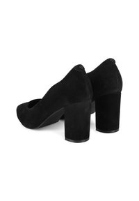 Pantofi negri din suede cu toc pătrat, cu vârf rotund și un design decupat la partea superioară. Au o textură netedă și un detaliu cu logo pe spate.