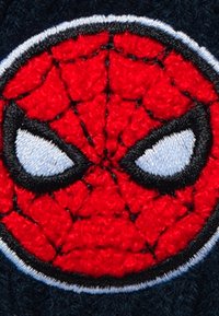 Parche bordado en rojo y negro que presenta la cara de Spider-Man con ojos blancos y contornos en negro, sobre un fondo azul oscuro.