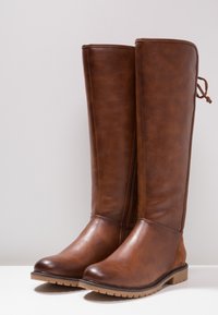 Brązowe syntetyczne skórzane kozaki do kolan z bocznym zamkiem błyskawicznym i teksturowanym wykończeniem, z solidną gumową podeszwą i detalem w postaci sznurka.