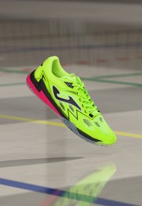Scarpa da atletica gialla neon con accenti neri e suola rosa, caratterizzata da una superficie testurizzata, un motivo a zigzag e un design con lacci sicuri.