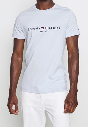 Jasnoniebieska bawełniana koszulka z krótkim rękawem, okrągłym dekoltem i czarnym logo "TOMMY HILFIGER EST. 1985" na wysokości klatki piersiowej. Miękka w dotyku.