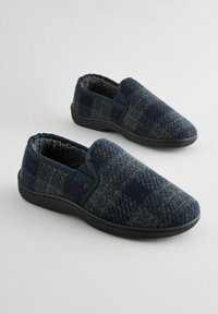 Marineblå og mørkegrå ternede slippers med blødt, pelsagtigt indre, elastiske sidelapper og en sort gummisål for godt greb.