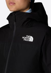 Czarna kurtka North Face z wysokim kołnierzem, zamkiem z przodu, regulowanymi sznureczkami i wyraźnym białym logo na piersi.