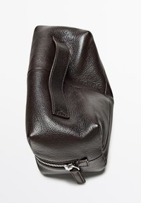 Borsa in pelle marrone scuro con superficie testurizzata, dotata di chiusura con cerniera e manico laterale per il trasporto. Design liscio e strutturato.