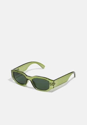 Gafas de sol verdes translúcidas con montura rectangular, lentes verde oscuro y un acento de logotipo en el lateral. Textura suave y diseño moderno.