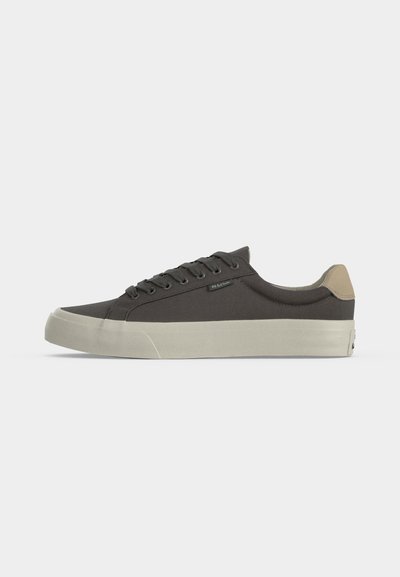 Baskets basses gris foncé avec un patch beige au talon, des lacets gris foncé assortis et une épaisse semelle en caoutchouc blanc cassé.