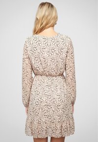 Robe légère à motifs floraux, rose pâle, avec des manches longues, une taille froncée et un ourlet festonné. Fabriquée en tissu transparent avec une texture subtile.
