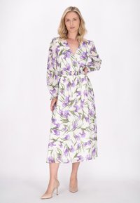 Rochie albă cu un model floral violet, cu mâneci lungi din material transparent, decolteu în V și talie elastică. Asortată cu tocuri neutre.