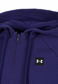 Navyblaue Zip-Hoodie aus weichem Material, mit einem schwarzen quadratischen Logo auf der Brust und strukturierten Kordeln für die Kapuze.