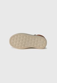 Semelle de chaussure en caoutchouc avec un motif hexagonal, de couleur beige clair, dotée d'un bord arrondi et d'une surface antidérapante texturée.