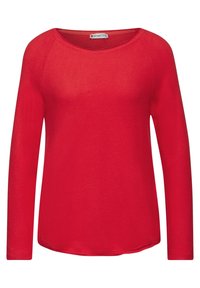 Czerwona koszula z długim rękawem wykonana z miękkiego materiału, z dekoltem w kształcie litery U i zaokrąglonym dołem. Casualowy fason z rękawami raglanowymi.
