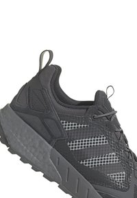 Fekete sportcipő texturált hálós felsőrésszel, megerősített sarkal, fényvisszaverő részletekkel és különböző mintázatú robusztus gumitalpval.