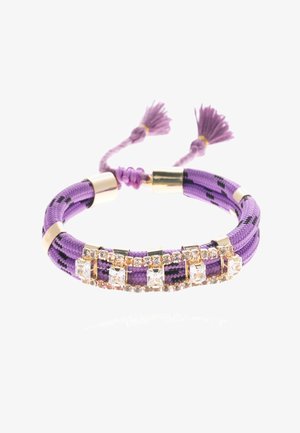 Bracelet tressé violet avec accents dorés et cristaux clairs. Fini avec des pompons décoratifs à chaque extrémité. Matériau texturé.