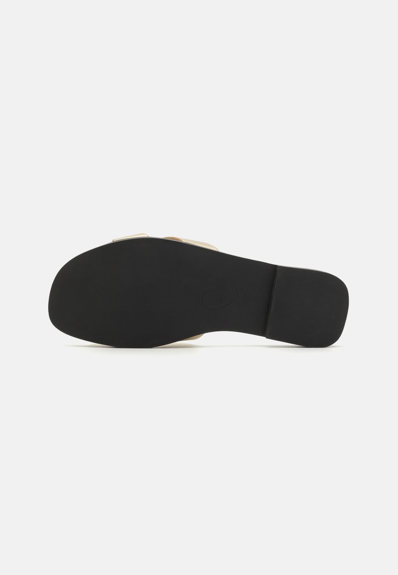 Flache Schuhsohle mit einer schwarzen Gummisohle, die eine glatte Textur aufweist, und einem obereren Abschnitt in heller Farbe mit strukturierten Designdetails.
