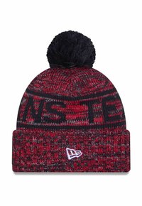 Knit beanie in red and black with a textured pattern, featuring a black pom-pom on top and a white logo at the front.