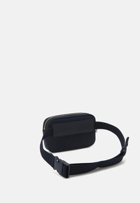 Borsa rettangolare nera con finitura testurizzata, dotata di chiusura con zip e tracolla in tessuto regolabile con fibbia in plastica.