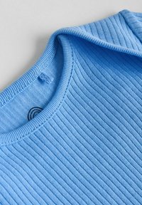 Svijetloplavi tkanje rebrastog pletiva s okruglim izrezom i malim detaljem u obliku tkanine u obliku petlje blizu ovratnika na svijetloj podlozi.