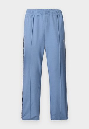 Šviesiai mėlynos sportinės kelnės su elastinga juosmens juosta, šoninėmis juostelėmis su baltais deimantų raštais ir mažu baltu Umbro logotipu kairiajame šlaunyje.