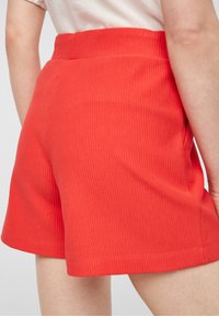 Rode geribbelde shorts met een brede tailleband, hebben een gladde textuur en een ontspannen pasvorm, eindigend net boven het midden van de dij met een afgewerkt rand.