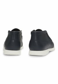 Scarpe nere in pelle con finitura testurizzata, design alto e suola in gomma bianca. Presentano un collare liscio e uno stile minimalista.