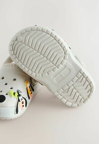 Sabots blancs ornés de graphismes de dessins animés de Dingo et de Pluto, avec des trous de ventilation et une semelle texturée pour une meilleure adhérence.