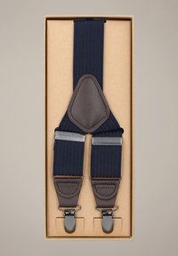 Granatowe szelki wykonane z teksturowanego materiału, z brązowymi skórzanymi akcentami i srebrnymi metalowymi klipsami. Zapakowane w beżowe pudełko.