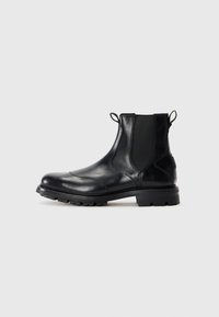 Botas Chelsea de cuero negro con paneles laterales elásticos, punta redondeada y suela robusta; cuenta con lengüetas en la parte trasera para facilitars su puesta.