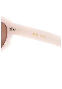 Rozā plastmasas saulesbrilles ar brūnām lēcām, kurām ir metāla eņģe un zelta drukājums, kas norāda uz zīmolu un UV aizsardzību.