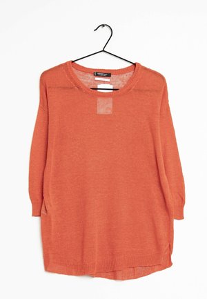 Maglione arancione a maniche lunghe, dalla vestibilità ampia, con scollatura tonda e spacchi laterali. Presenta un pannello leggermente trasparente sul petto.