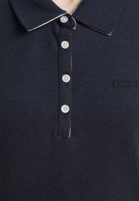 Námořnická modrá polo košile s texturovanou tkaninou, klasickým límcem, pěti stříbrnými knoflíky a decentním vyšitým logem Barbour.