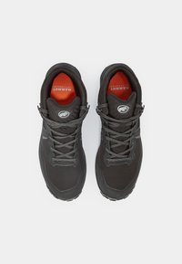 Zapatillas de senderismo negras con una parte superior sintética suave, cordones grises y una plantilla naranja. Suela texturizada para tracción. Logo en el talón.