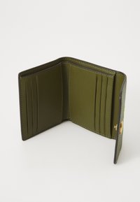 Green leather wallet interior with multiple card slots, a smooth finish, and a snap closure. The edges are stitched in a contrasting color.
