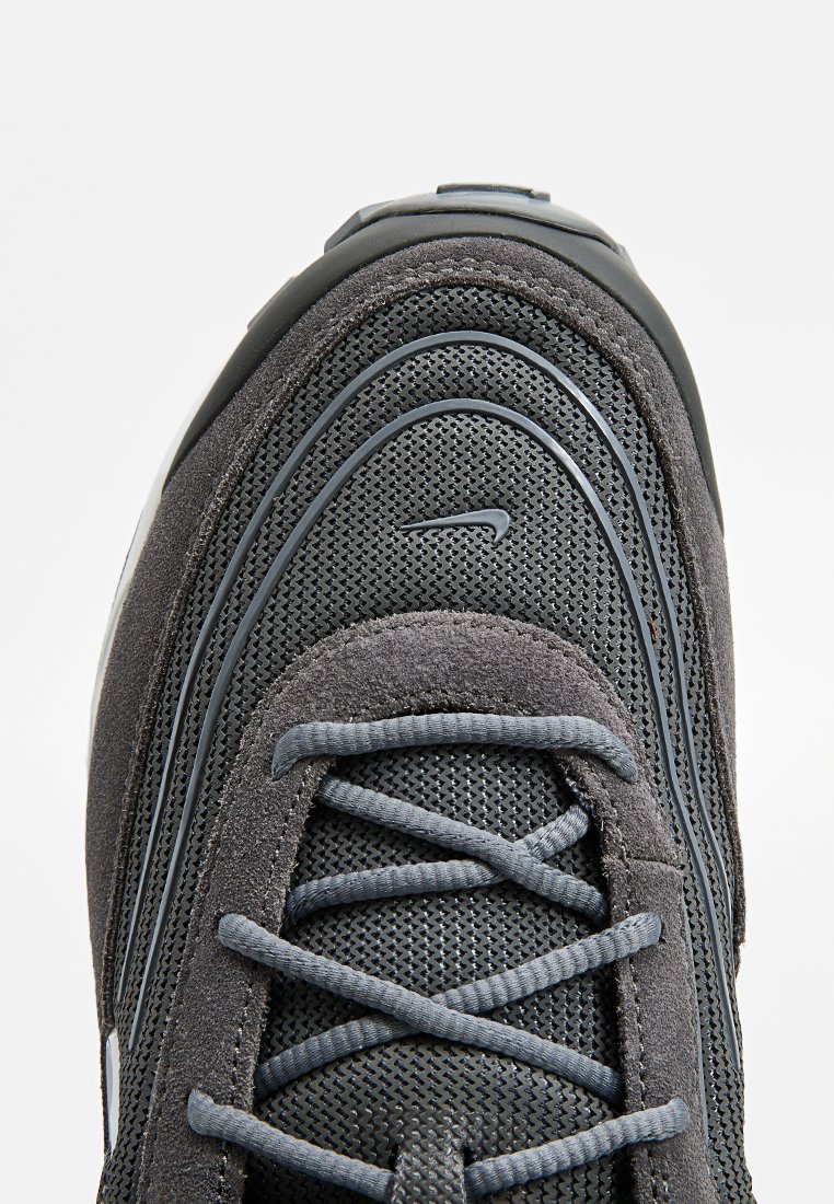 Baskets grises avec une tige en mesh et en suède, bout rond, surfaces texturées et lacets gris. Lignes courbées notables sur les côtés.