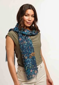 Sciarpa con stampa floreale in blu scuro e fiori multicolori. Tessuto leggero e trasparente con bordi frangiati, drappeggiata elegantemente attorno al collo.