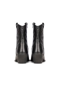 Botas negras de cuero hasta el tobillo, con un diseño de remolino cosido, dos cremalleras laterales y un tacón en cuña texturizado. Acabado suave sin adornos visibles.
