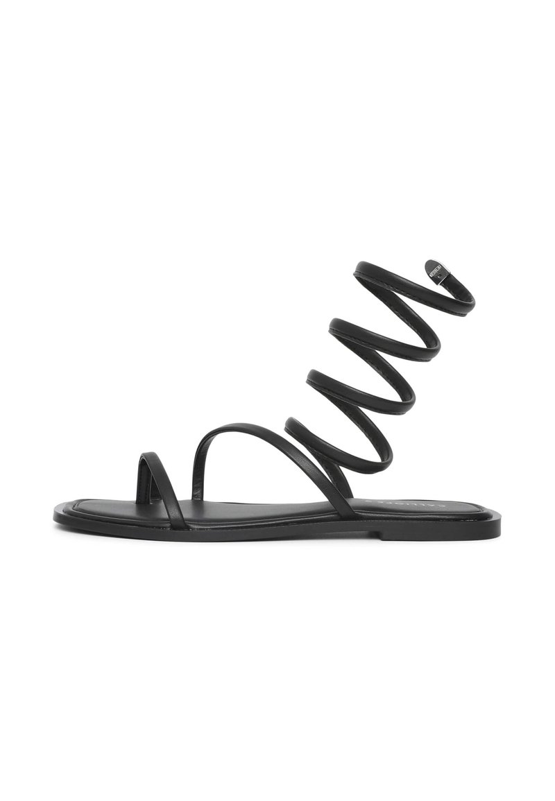 Schwarze Sandale mit flacher Sohle, dünnen Riemen und einem spiralförmigen Design, das nach oben verläuft. Hergestellt aus glattem Material und mit minimalistischen Akzenten.