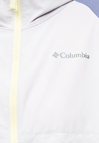 Λευκό μπουφάν με κίτρινο φερμουάρ και το λογότυπο της Columbia σε γκρι στην περιοχή του δεξιού στήθους.