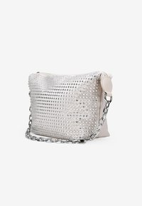 Bolso de piel blanca con tachuelas plateadas, superficie texturizada y correa de cadena plateada. Cierre de cremallera en la parte superior; diseño ligeramente caído.