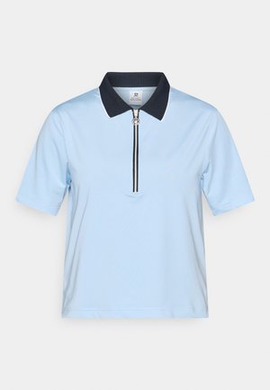 Svijetlo plava polo majica s tamnoplavim ovratnikom, kratkim rukavima i četvrtim patentnim zatvaračem koji ima detalj od srebrne boje i bijelo obrubljivanje na ovratniku.