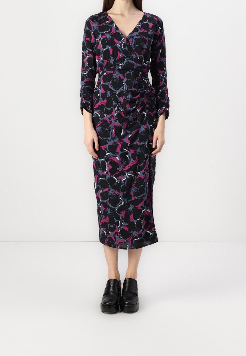 Black dress with a floral pattern in purple and blue, featuring a V-neck, long sleeves, and a knee-length hem. Worn with black platform shoes.