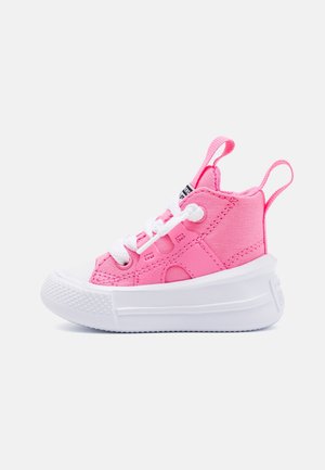Sneaker rosa da bambino con tomaia alta, suola spessa bianca, lacci bianchi, asole di traino su tallone e linguetta.