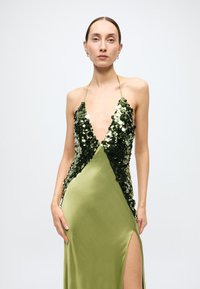 Green sequin-embellished evening dress with a deep V-neck, halter straps, and a high side slit in smooth satin fabric.