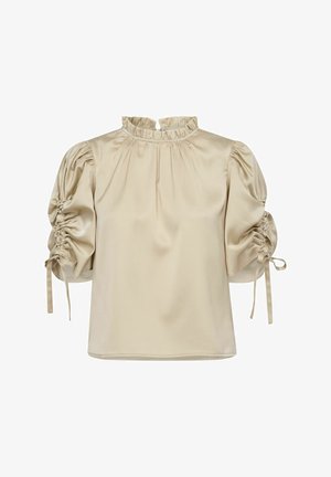 Blouse beige à manches courtes avec un col volanté et des manches bouffantes ; elle présente des cordons aux poignets et une texture lisse, semblable à du satin.