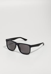 Ochelari de soare din plastic negru cu lentile de culoare gri închis, formă pătrată, rame groase și accente hardware minimale pe tâmple.