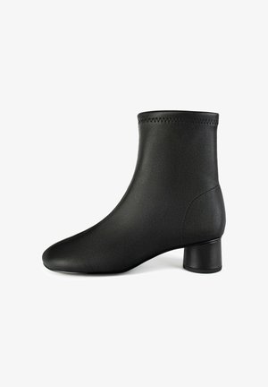 Bottine noire en cuir lisse avec un bout arrondi et un petit talon cylindrique. Présente des coutures décoratives sur le bord supérieur.