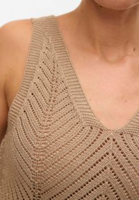 Top de tirantes de punto color beige con escote en V y patrón de chevron, que presenta detalles de calado y un acabado texturizado.