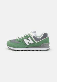 Baskets en daim vert et en maille grise avec des accents blancs et gris, comportant un col rembourré, une semelle extérieure durable et un logo "N" bien visible.