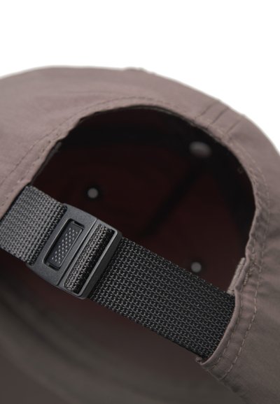 Artimas juodos reguliuojamos juostos su plastiko sagtimi, esančios ant rudos audinio kepurės nugaros.