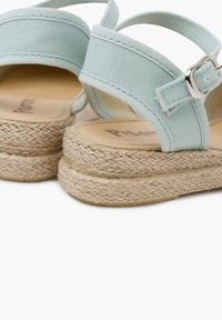Sandales en tissu bleu clair avec une semelle en jute de style espadrille, sangle ajustable avec une boucle en métal argenté, et une finition lisse et texturée.